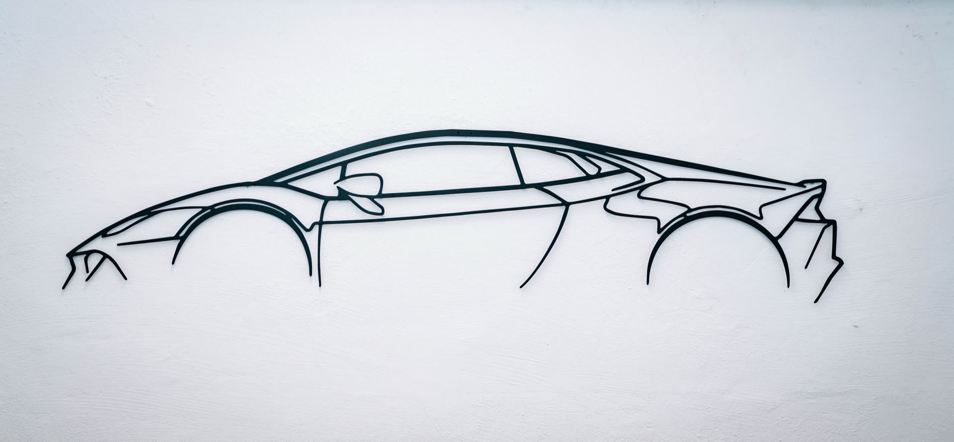 Supersportwagen-Silhouette als Drahtskulptur an der Werkstattwand